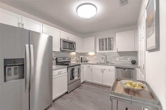 3604 Clawson Rd Unit 204, Austin, TX 78704 - kitchen with appliances with stainless steel finishes, white cabinetry, decorative backsplash, light countertops, and light wood-style flooring