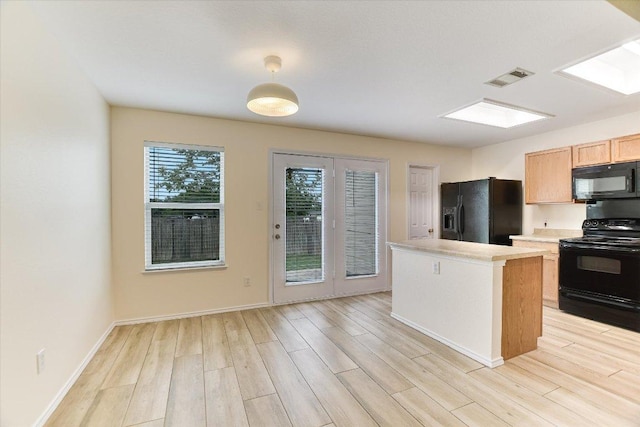 210 Deercreek Ln, Leander, TX 78641 - kitchen with black appliances, light countertops, light wood finished floors, a center island, and a skylight