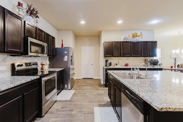 115 San Bernard Trl, Hutto, TX 78634 - kitchen featuring stainless steel appliances, backsplash, light wood-style floors, recessed lighting, and a kitchen island with sink