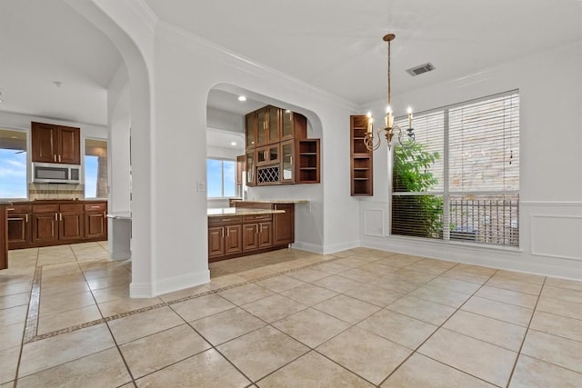 5724 Brittlyns Ct, Austin, TX 78730 - unfurnished dining area with light tile patterned flooring, a chandelier, ornamental molding, inlaid floor details, and arched walkways