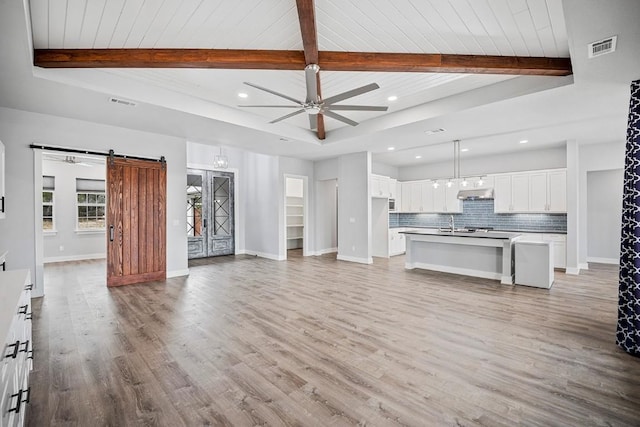 21603 Thomas Cv, Lago Vista, TX 78645 - unfurnished living room with a barn door, ceiling fan, beamed ceiling, light wood-style floors, and recessed lighting