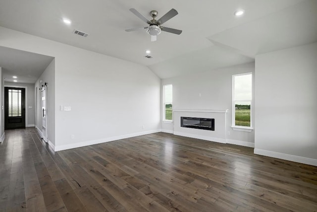 182 Alonzo Dr, Del Valle, TX 78617 - unfurnished living room featuring dark wood-style floors, a glass covered fireplace, ceiling fan, lofted ceiling, and recessed lighting