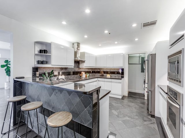 40 N Interstate 35 Unit 2D1, Austin, TX 78701 - kitchen featuring wall chimney exhaust hood, stainless steel appliances, a peninsula, open shelves, and white cabinets