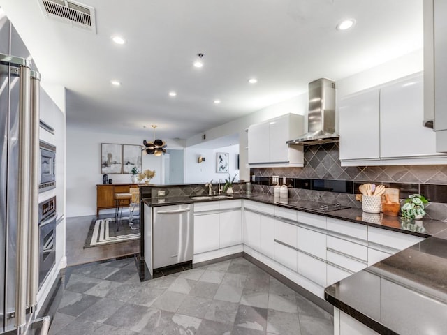 40 N Interstate 35 Unit 2D1, Austin, TX 78701 - kitchen with wall chimney range hood, stainless steel appliances, white cabinetry, tasteful backsplash, and a peninsula