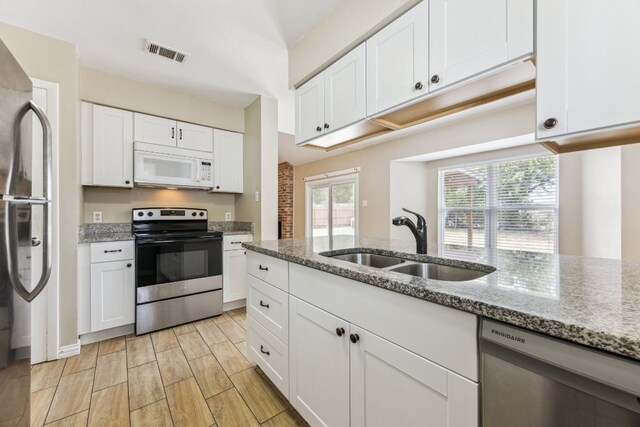 508 Buffalo Pass, Round Rock, TX 78681 - kitchen with appliances with stainless steel finishes, white cabinets, light stone countertops, and wood finish floors