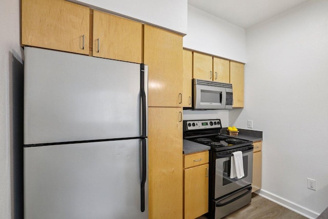 1201 Grove Blvd Unit 1502, Austin, TX 78741 - kitchen featuring appliances with stainless steel finishes, wood finished floors, dark countertops, and light brown cabinetry