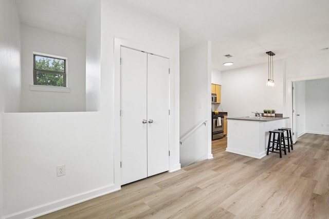 1201 Grove Blvd Unit 1502, Austin, TX 78741 - kitchen featuring stainless steel appliances, a breakfast bar area, light wood-style flooring, dark countertops, and a peninsula