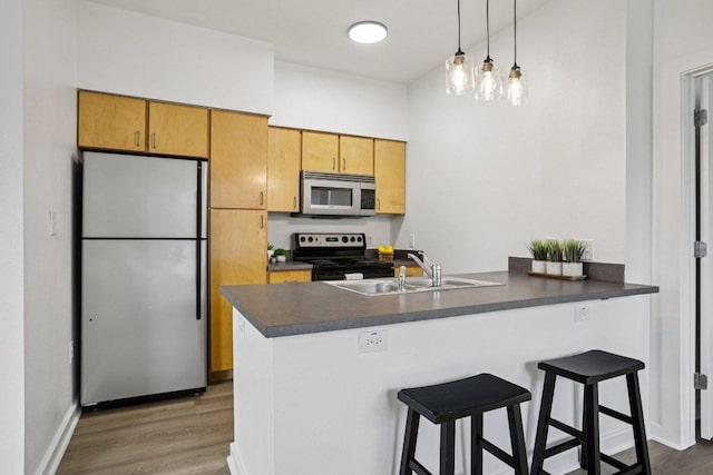 1201 Grove Blvd Unit 1502, Austin, TX 78741 - kitchen with stainless steel appliances, a peninsula, wood finished floors, dark countertops, and a breakfast bar