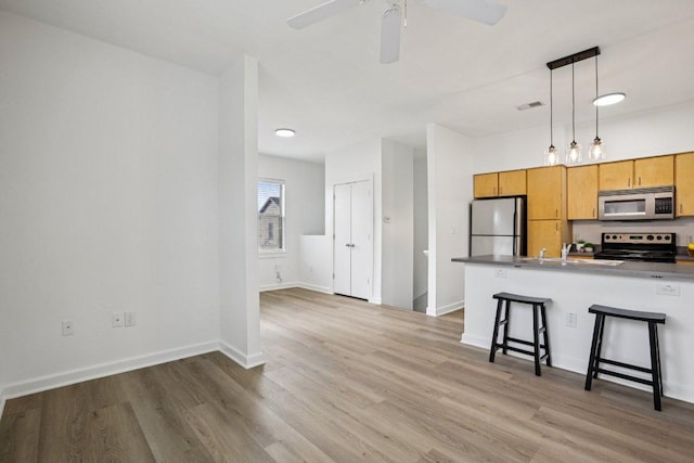 1201 Grove Blvd Unit 1502, Austin, TX 78741 - kitchen featuring stainless steel microwave, freestanding refrigerator, range with electric cooktop, a kitchen bar, and light wood-style flooring
