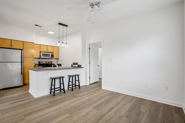 1201 Grove Blvd Unit 1502, Austin, TX 78741 - kitchen with stainless steel appliances, a peninsula, light wood-style flooring, decorative light fixtures, and a breakfast bar