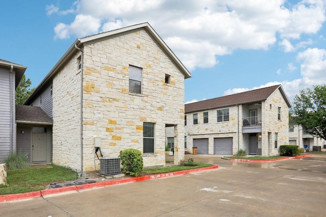 1201 Grove Blvd Unit 1502, Austin, TX 78741 - view of front of home featuring stone siding, a garage, driveway, and a balcony