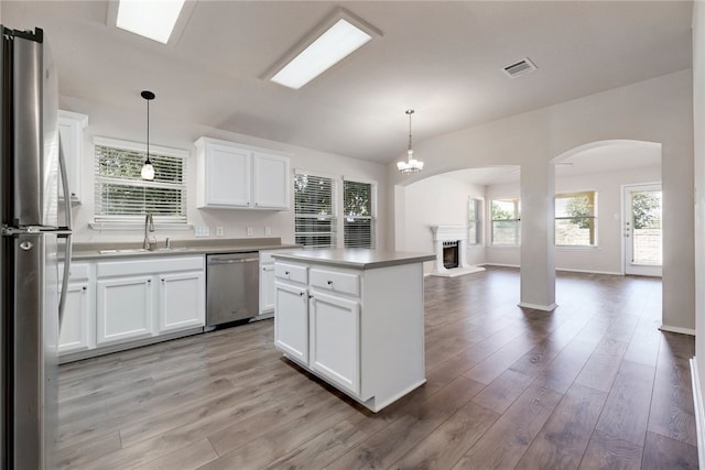 14400 Mowsbury Dr, Austin, TX 78717 - kitchen with appliances with stainless steel finishes, arched walkways, a fireplace with raised hearth, and light wood-style flooring