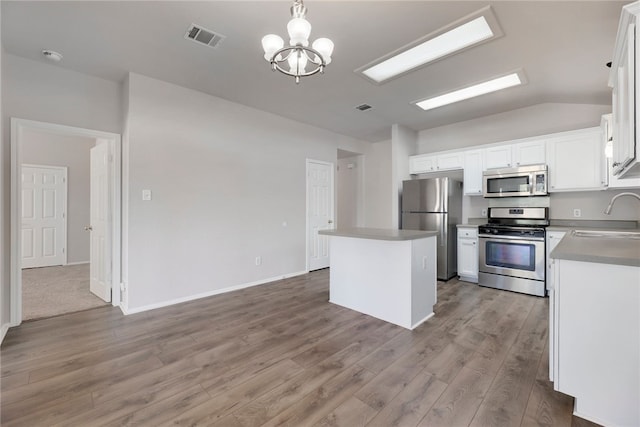 14400 Mowsbury Dr, Austin, TX 78717 - kitchen featuring stainless steel appliances, a center island, wood finished floors, a chandelier, and white cabinets