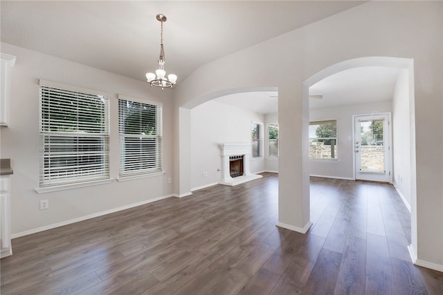 14400 Mowsbury Dr, Austin, TX 78717 - unfurnished living room featuring a fireplace with raised hearth, dark wood-style flooring, arched walkways, and a chandelier
