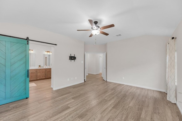 815 Clarence Bohls Ln, Pflugerville, TX 78660 - unfurnished bedroom with a barn door, light wood finished floors, lofted ceiling, ensuite bath, and a ceiling fan