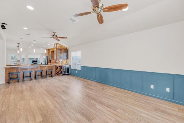 815 Clarence Bohls Ln, Pflugerville, TX 78660 - living room with wine cooler, ceiling fan, light wood-style floors, a decorative wall, and a wainscoted wall