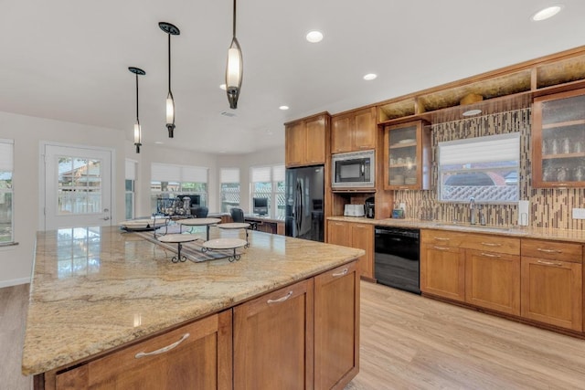 815 Clarence Bohls Ln, Pflugerville, TX 78660 - kitchen featuring black appliances, brown cabinetry, light stone countertops, a kitchen island, and recessed lighting