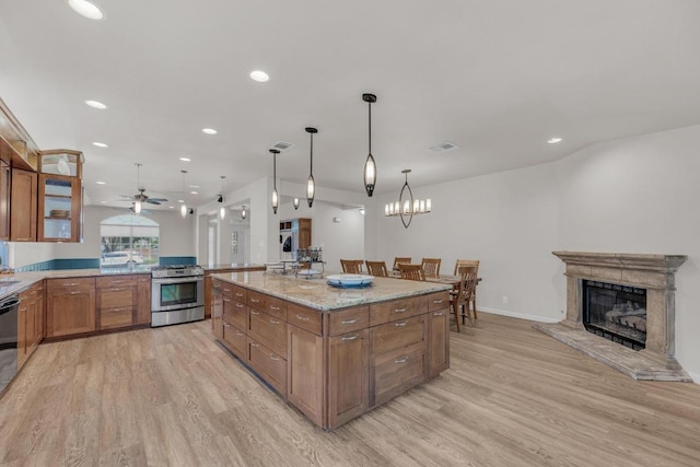 815 Clarence Bohls Ln, Pflugerville, TX 78660 - kitchen featuring stainless steel range with gas stovetop, light wood-style flooring, brown cabinetry, recessed lighting, and ceiling fan