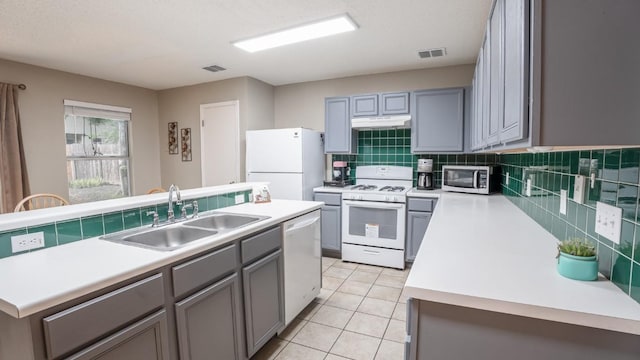 8086 Thaxton Rd, Austin, TX 78747 - kitchen featuring white appliances, under cabinet range hood, light countertops, decorative backsplash, and gray cabinets