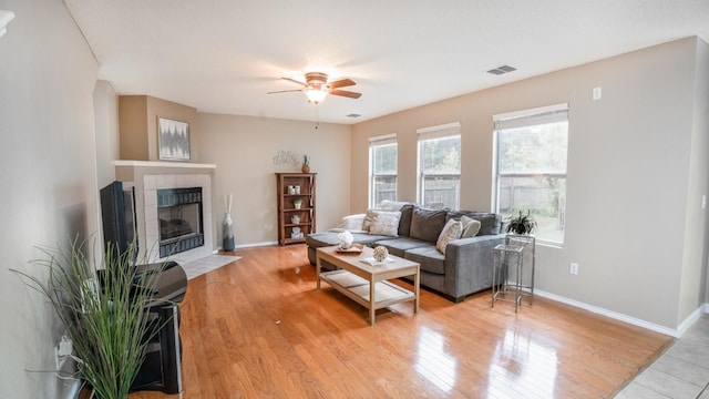 8086 Thaxton Rd, Austin, TX 78747 - living room featuring a tile fireplace, ceiling fan, and light wood-style floors