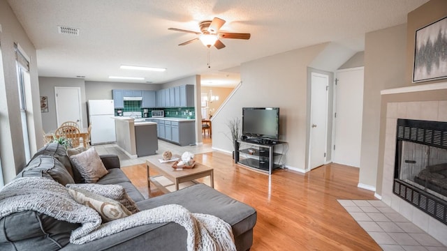 8086 Thaxton Rd, Austin, TX 78747 - living area featuring light wood-style flooring, a fireplace, ceiling fan, and healthy amount of natural light