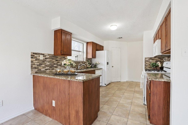 13302 Black Canyon Dr, Austin, TX 78729 - kitchen with white appliances, backsplash, light tile patterned floors, a peninsula, and brown cabinets