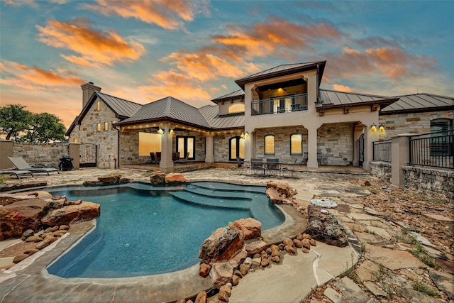 1073 Las Brisas Dr, Canyon Lake, TX 78133 - rear view of house with a standing seam roof, a metal roof, a balcony, and stone siding