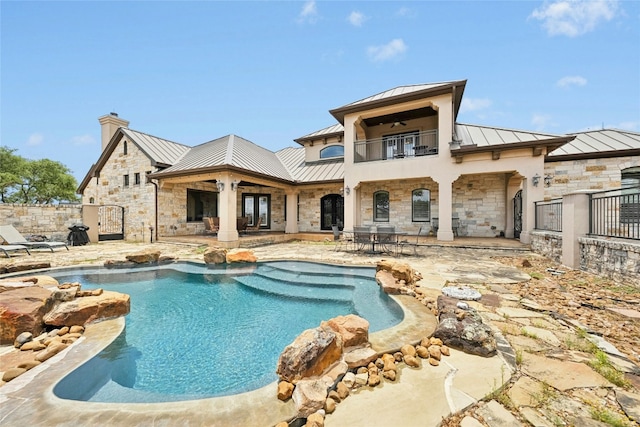 1073 Las Brisas Dr, Canyon Lake, TX 78133 - rear view of house with a standing seam roof, a metal roof, a balcony, and stone siding