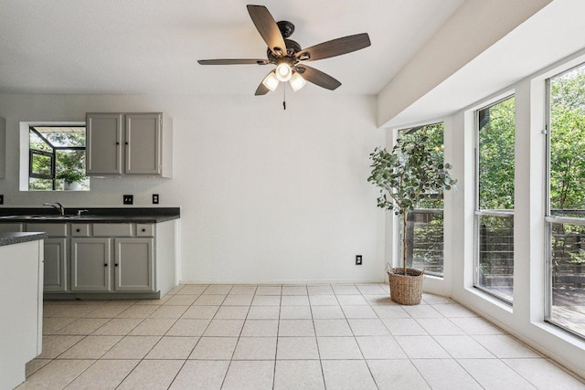 1613 J J Seabrook Dr, Austin, TX 78721 - kitchen featuring gray cabinetry, dark countertops, a ceiling fan, and light tile patterned floors
