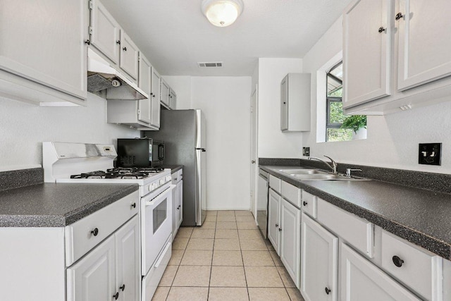 1613 J J Seabrook Dr, Austin, TX 78721 - kitchen featuring white gas range, dark countertops, dishwasher, light tile patterned floors, and under cabinet range hood