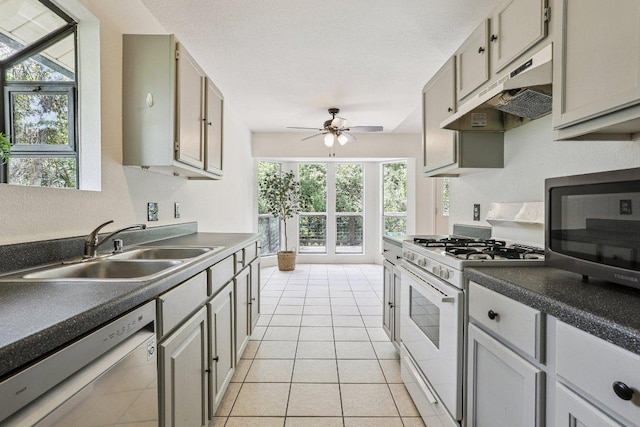1613 J J Seabrook Dr, Austin, TX 78721 - kitchen with appliances with stainless steel finishes, under cabinet range hood, a ceiling fan, light tile patterned floors, and dark countertops