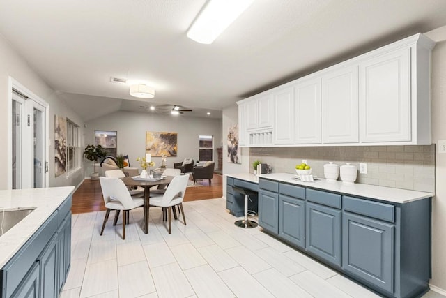 2716 Cradlerock Ter, Austin, TX 78748 - kitchen featuring blue cabinets, white cabinetry, tasteful backsplash, and vaulted ceiling