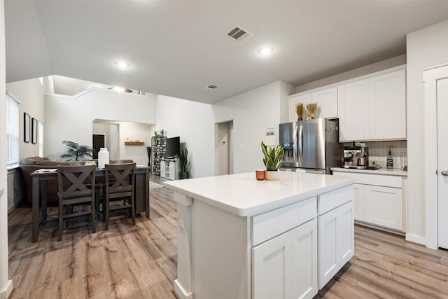 209 Lambert St, Leander, TX 78641 - kitchen featuring stainless steel fridge, light wood-type flooring, tasteful backsplash, white cabinetry, and a kitchen island