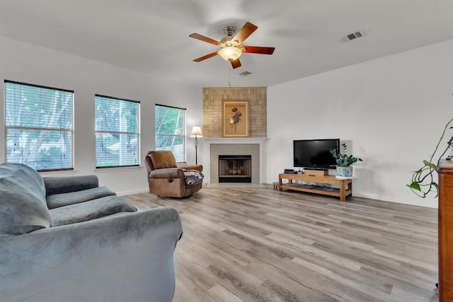2101 Charlotte Estates Dr, Austin, TX 78744 - living room featuring ceiling fan, a tiled fireplace, and light wood-type flooring