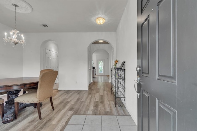 2101 Charlotte Estates Dr, Austin, TX 78744 - entrance foyer featuring arched walkways, light wood-type flooring, and a chandelier