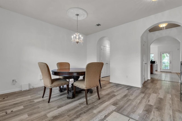 2101 Charlotte Estates Dr, Austin, TX 78744 - dining area featuring light wood finished floors, arched walkways, and a chandelier