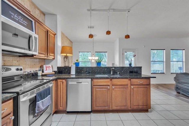 2101 Charlotte Estates Dr, Austin, TX 78744 - kitchen with appliances with stainless steel finishes, a chandelier, rail lighting, backsplash, and open floor plan