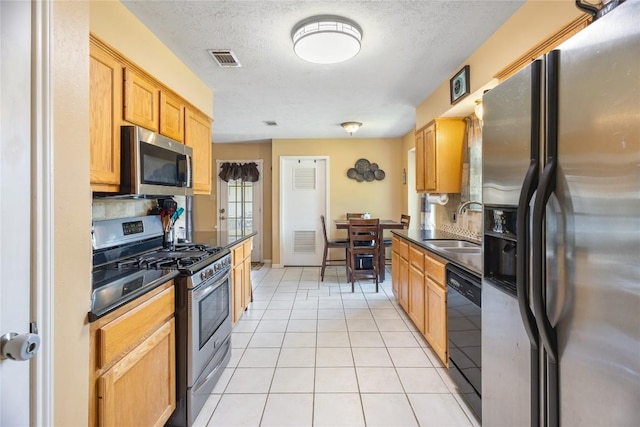 5804 Sheffield Terrace Ln, Bryan, TX 77802 - kitchen featuring stainless steel appliances, dark countertops, light tile patterned floors, decorative backsplash, and a textured ceiling