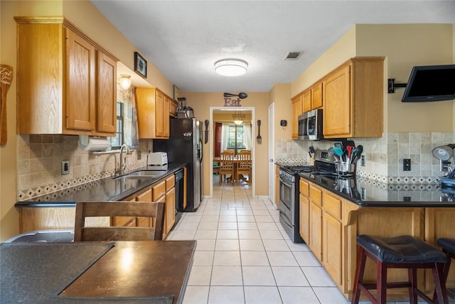 5804 Sheffield Terrace Ln, Bryan, TX 77802 - kitchen with appliances with stainless steel finishes, dark countertops, backsplash, and light tile patterned floors