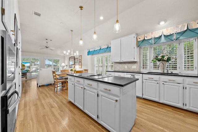 10839 Redmond Rd, Austin, TX 78739 - kitchen with dark countertops, white dishwasher, light wood finished floors, white cabinets, and a kitchen island