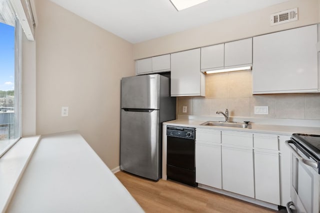 1840 Burton Dr Unit 155, Austin, TX 78741 - kitchen featuring appliances with stainless steel finishes, light wood-style floors, decorative backsplash, and white cabinetry