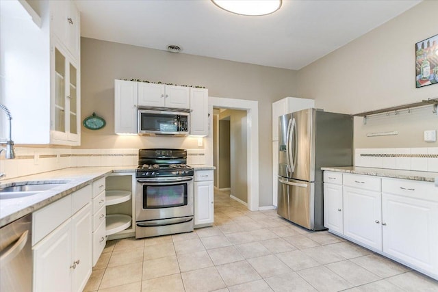 4415 Ave D Ave, Austin, TX 78751 - kitchen featuring stainless steel appliances, white cabinets, light stone counters, and light tile patterned floors