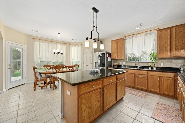4004 Callabero Cv, Round Rock, TX 78681 - kitchen featuring stainless steel fridge, brown cabinets, decorative backsplash, and plenty of natural light