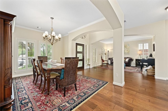 4004 Callabero Cv, Round Rock, TX 78681 - dining space with arched walkways, a chandelier, wood finished floors, and crown molding