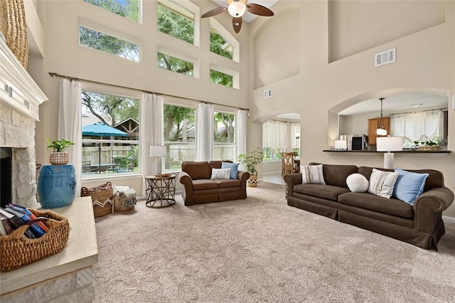 4004 Callabero Cv, Round Rock, TX 78681 - living room with arched walkways, carpet, ceiling fan, a high ceiling, and a fireplace