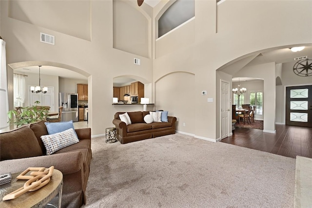 4004 Callabero Cv, Round Rock, TX 78681 - living room featuring a chandelier, a towering ceiling, arched walkways, and dark colored carpet