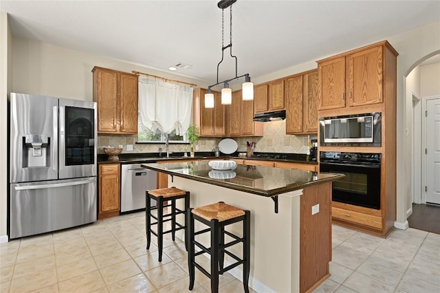 4004 Callabero Cv, Round Rock, TX 78681 - kitchen featuring stainless steel appliances, a kitchen island, backsplash, pendant lighting, and arched walkways