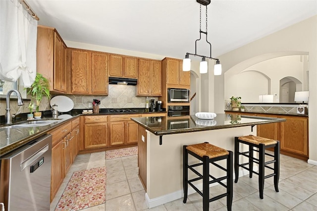 4004 Callabero Cv, Round Rock, TX 78681 - kitchen featuring black appliances, under cabinet range hood, backsplash, a breakfast bar area, and a kitchen island