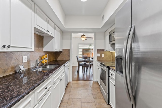 2704 San Pedro St Unit A16, Austin, TX 78705 - kitchen featuring appliances with stainless steel finishes, white cabinets, a ceiling fan, dark stone countertops, and decorative backsplash