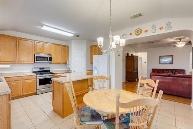 1312 Kothman Dr, Hutto, TX 78634 - kitchen with stainless steel appliances, lofted ceiling, light tile patterned floors, light countertops, and a center island